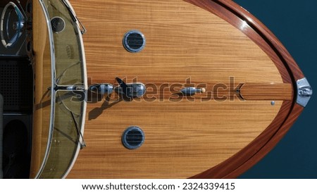 The front of a wooden boat on a blue background top view. Helm boat. Expensive wooden lacquered part of the boat. Fore deck. Wooden deck on a blue background top view. Royalty-Free Stock Photo #2324339415