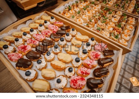 Assortment of sweet and colorful eclairs on wooden plate