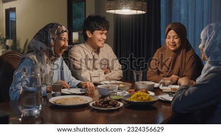 Happy Asia muslim parent and their kids Ramadan dinner together in dining room at home. Family of two generation catering celebration end of Eid al-Fitr togetherness at home. Hari Raya family reunion. Royalty-Free Stock Photo #2324356629
