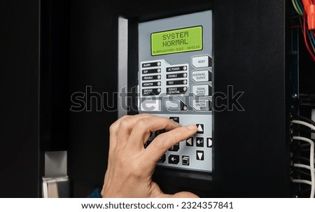 Technician using fire alarm control panel in service room. Single-stage fire alarm system in strata, residential or commercial building. Yearly checkup or trouble shooting problem. Selective focus. Royalty-Free Stock Photo #2324357841
