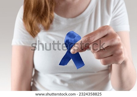 Closeup of blue awareness ribbon being held by young caucasian woman for Diabetes awareness month.