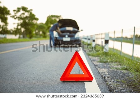 Red emergency stop sign with broken black car on the road. close-up red emergency stop sign with broken down car on the road waiting to be repaired. road safety concept