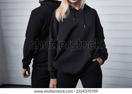 Stylish Hoodie Mockup. Fashionable Autumn Streetwear for Young Couples. Woman and man wear black hoodies without a logo. No logo basic sportswear. Long sleeve sweatshirt mockup Royalty-Free Stock Photo #2324370709