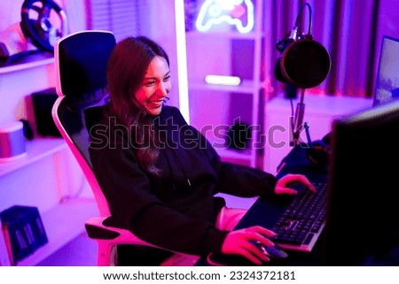 Asian pretty gamer girl typing keyboard and use mouse while sitting ergonomic chair and playing video game challenge in entertainment neon light room