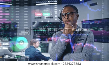 African American investment specialist analyzes real-time stocks in office. 3D graphics of cryptocurrency charts on glass wall. Futuristic VFX animation. Employees work on computers on background.