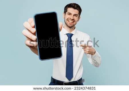 Young employee business man corporate lawyer wear classic formal shirt tie work in office hold use show blank screen workspace area mobile cell phone isolated on plain blue background studio portrait Royalty-Free Stock Photo #2324374831