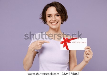 Young fun smiling happy woman 20s with bob haircut wearing white t-shirt pointing index finger on gift certificate coupon voucher card for store isolated on pastel purple background studio portrait.