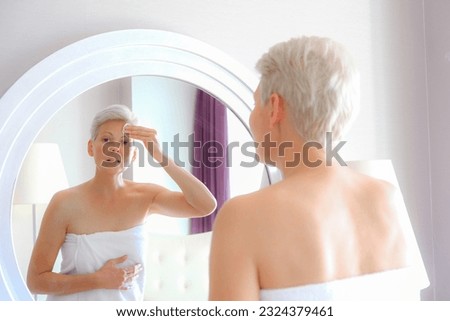 Young blonde woman with freckles cleaning her fas with beauty pod using tonic in the morning. Spa procedure at home, staying in towel Royalty-Free Stock Photo #2324379461