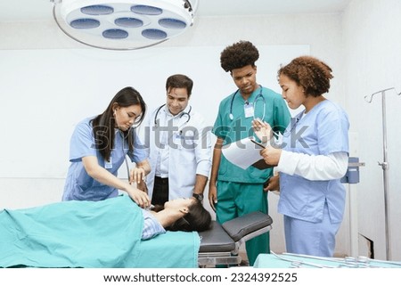 Senior doctor training a group of medical students using a patient simulator in a hospital. Experienced health professional providing medical education to young men and women dressed in scrubs.
