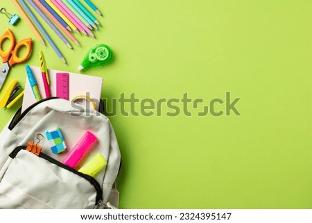 Back to school concept. Flat lay composition with backpack and school stationery on green background.