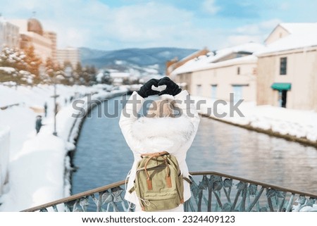 Woman tourist Visiting in Otaru, happy Traveler in Sweater sightseeing Otaru canal with Snow in winter season. landmark and popular for attractions in Hokkaido, Japan. Travel and Vacation concept Royalty-Free Stock Photo #2324409123