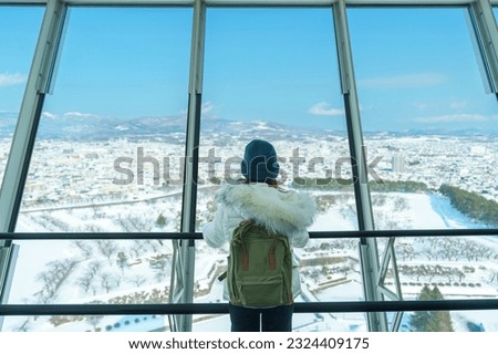 Woman tourist Visiting in Hakodate, Traveler in Sweater sightseeing view from Goryokaku Tower with Snow in winter. landmark and popular for attractions in Hokkaido, Japan.Travel and Vacation concept Royalty-Free Stock Photo #2324409175