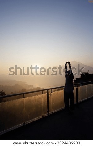 photo in the morning when a woman is enjoying the sunrise from the top of the building