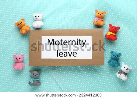 Envelope, note with words Maternity Leave and toys on turquoise fabric, flat lay