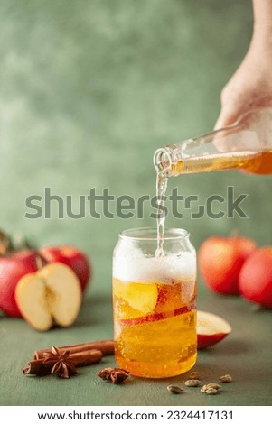 Boozy Refresing Cold Hard Apple Cider in a Pint Glass and Bottle on wooden table. Copy space Royalty-Free Stock Photo #2324417131