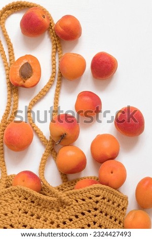 Fresh organic orange apricots in a yellow crochet bag on a white background. Healthy dieting eating concept.