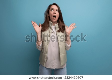 shocked caucasian young brunette woman in casual clothes with open mouth on studio background