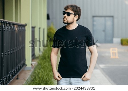 Young stylish bearded man  in a black T-shirt and sunglasses. Street photo
