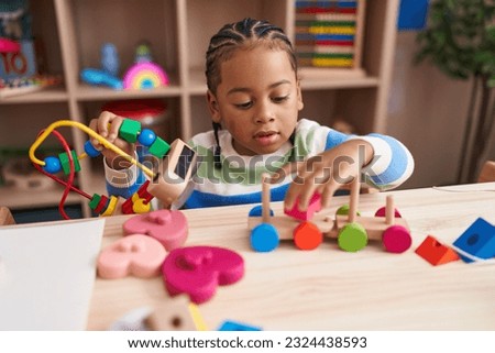African american boy playing with blocks train toy sitting on table at kindergarten Royalty-Free Stock Photo #2324438593
