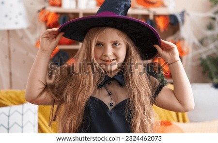 Adorable blonde girl wearing witch costume having halloween party at home