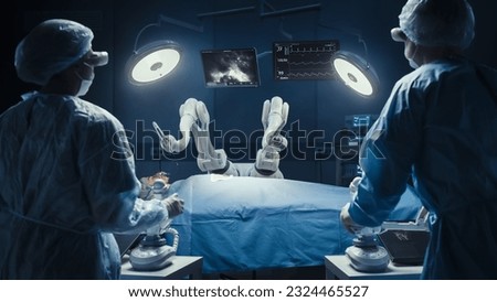 Two Surgeons Wearing Augmented Reality Headsets And Using High-Precision Remote Controlled Robot Arms To Operate On Patient In Futuristic Hospital. Doctors Working With Robotic Limbs, Observing Vitals Royalty-Free Stock Photo #2324465527