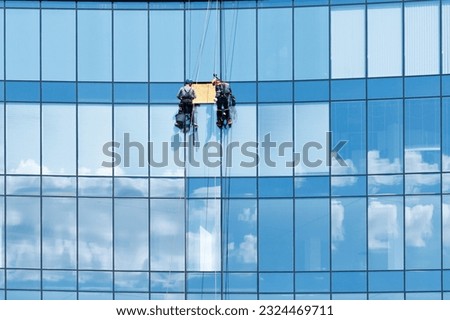 High-rise fitters repairing a glass panel in a window of a high-rise building. Royalty-Free Stock Photo #2324469711