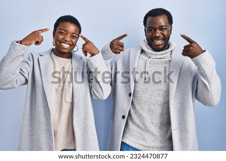 Young african american couple standing over blue background together smiling pointing to head with both hands finger, great idea or thought, good memory  Royalty-Free Stock Photo #2324470877