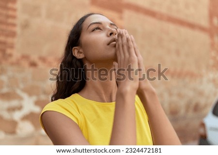 Young african american woman praying with closed eyes at street