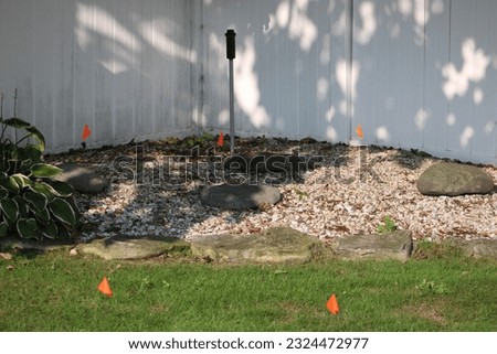 Orange flags that have been stuck into the ground on a construction site. They are used to mark underground utilities.