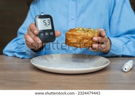 Woman showing glucose level and holding high carb food. Life with diabetes Royalty-Free Stock Photo #2324479443