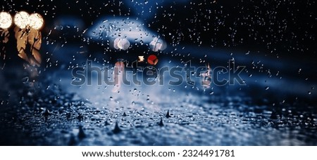 Rain shower on car windshield or car window and blurry road in background. Driving in rainy season. Rain drops on car mirror. Traffic road in evening rain. Drizzle raining decreases driving visibility Royalty-Free Stock Photo #2324491781
