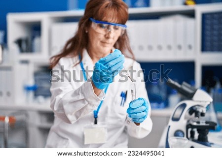 Middle age woman scientist measuring liquid at laboratory