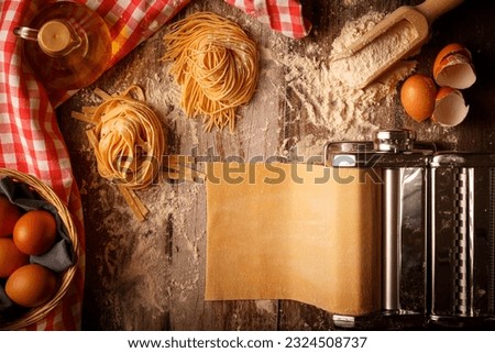Fresh pasta homemade preparation. Pasta machine and ingredients on a kitchen table. Top view
