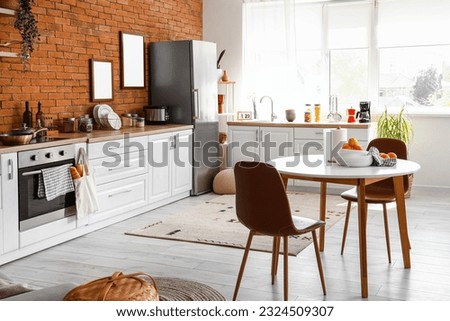 Interior of kitchen with stylish fridge, counters, table and chairs
