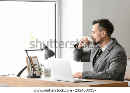Young businessman drinking water with dissolved tablet in office