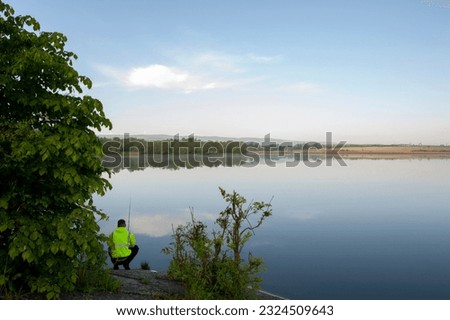 fisherman on the shore of the pond pulls a spinning fish on a sunny day