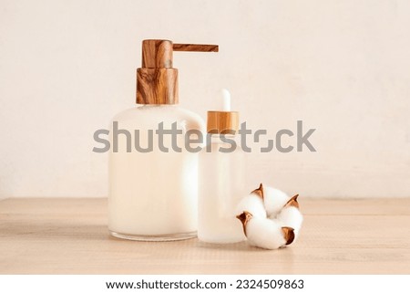 Bottles of cosmetic products and cotton flower on wooden background