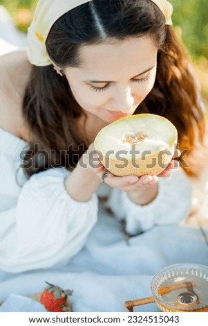 Beautiful young dark-haired woman on picnic in field. Model in stylish clothes with bicycle.