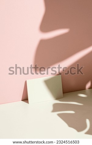 Business card mockup, template on pink and white background with tropical plant leaf shadow.