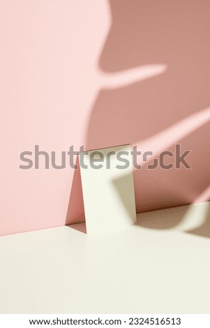 Business card mockup, template on pink and white background with monstera plant leaf shadow.
