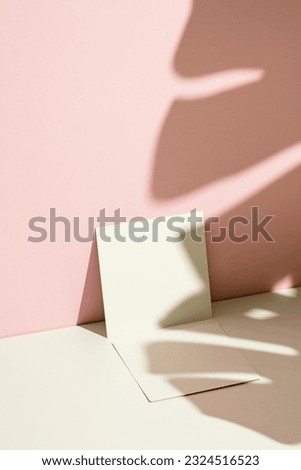 Business card mockup, template on pink and white background with monstera leaf shadow.