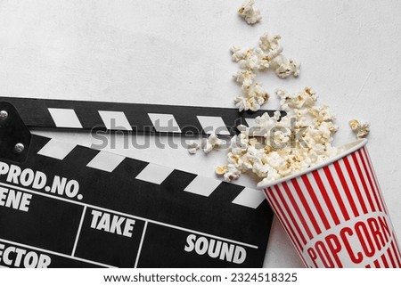 Bucket with tasty popcorn and clapperboard on white background