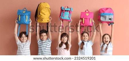 Many little students with schoolbags on beige background Royalty-Free Stock Photo #2324519201