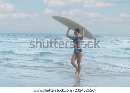 
Asian women wearing swimsuits hobby Warm up before exercise Stretching before exercise Practice surfing waves on a board in the sea on the beach in Thailand.