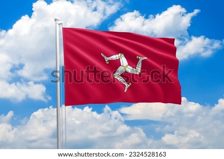 Isle of Man national flag waving in the wind on clouds sky. High quality fabric. International relations concept