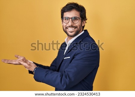Handsome latin man standing over yellow background pointing aside with hands open palms showing copy space, presenting advertisement smiling excited happy 