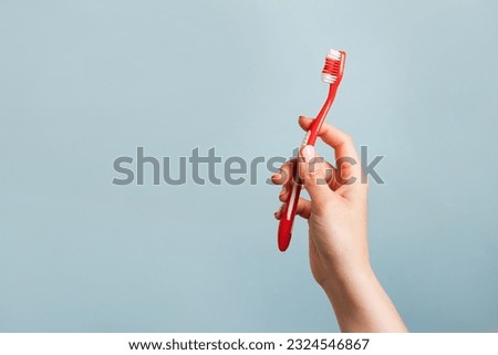 Woman holding red toothbrush against color blue background, copy space Royalty-Free Stock Photo #2324546867