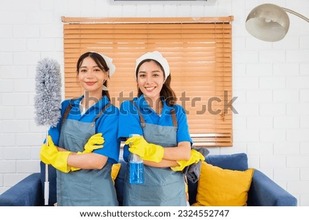 Portrait of two Asian young cleaning service women worker team working in house. Girls housekeeper cleaner, hold feather duster, foggy spray and rag with smile, looking at camera after finish chore. Royalty-Free Stock Photo #2324552747