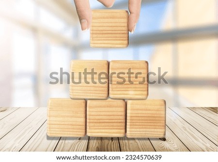 Hand stacking wooden cubes on table with copy space for input wording and infographic icon.