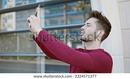 Young hispanic man make picture by the smartphone at street